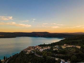 Scenic view of typical french village against a lake and sky during sunset