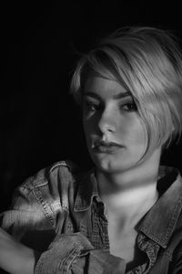 Close-up portrait of young woman against black background