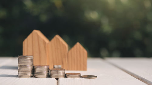 Close-up of stacked coins by wooden model homes on table
