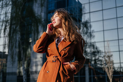 Young woman talking on the phone outdoors. girl having phone call on the street.