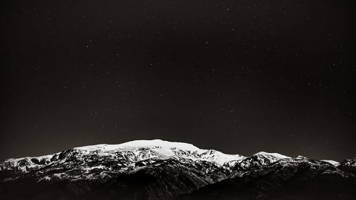 Scenic view of snowcapped mountains against sky at night