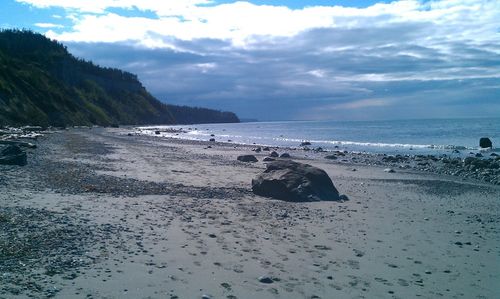 Scenic view of beach against cloudy sky