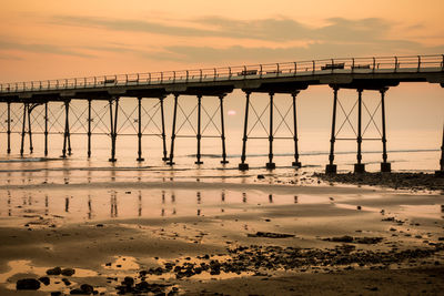 Bridge over sea against sky during sunset