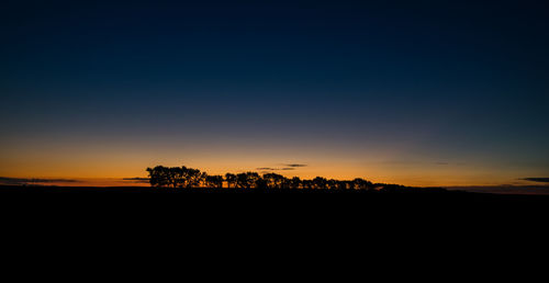 Silhouette landscape against clear sky during sunset