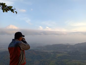 Man photographing on mountain against sky