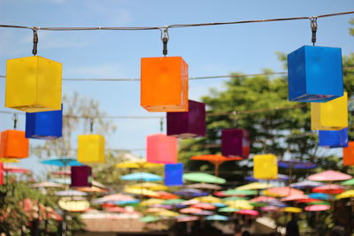 Low angle view of multi colored box shaped lanterns hanging against sky