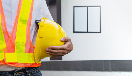 Rear view of man working against yellow wall