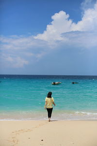 Rear view of woman on beach against sky