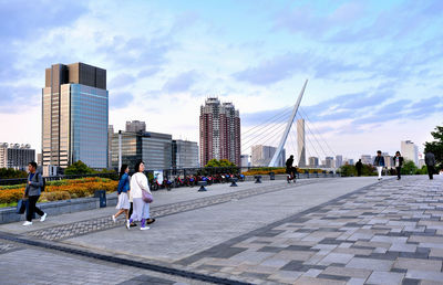 People walking on footpath against buildings in city