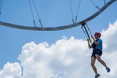 Low angle view of boy jumping against blue sky