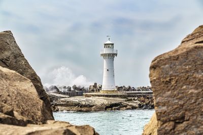 Lighthouse by sea against sky