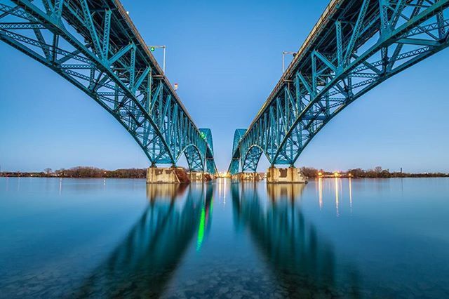 clear sky, water, blue, connection, transportation, built structure, long, bridge - man made structure, engineering, waterfront, river, reflection, diminishing perspective, copy space, architecture, tranquility, bridge, outdoors, no people, sea