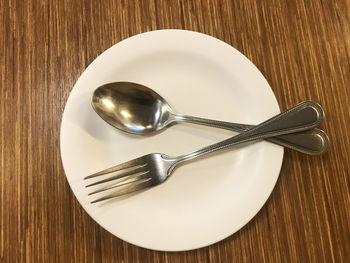 High angle view of cutlery in plate on wooden table