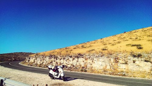 People on road against clear blue sky