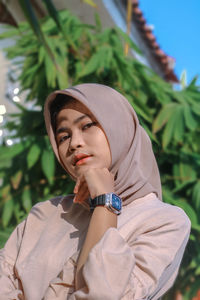 Portrait of young woman standing against plants