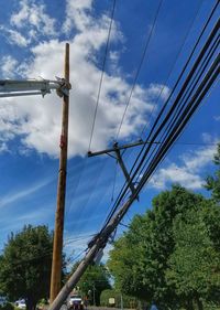 Low angle view of electricity pylon against cloudy sky