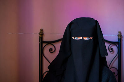 Portrait of woman wearing burka against wall