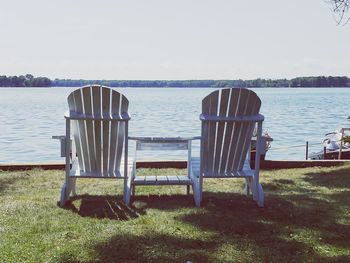 Empty chairs on beach against sky