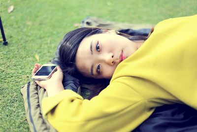 Close-up portrait of happy girl lying on mobile phone