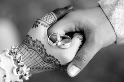 Cropped image of couple with wedding rings holding hands