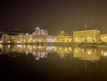 Reflection of buildings in lake at night