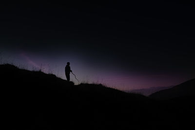 Silhouette man standing on mountain against sky during sunset