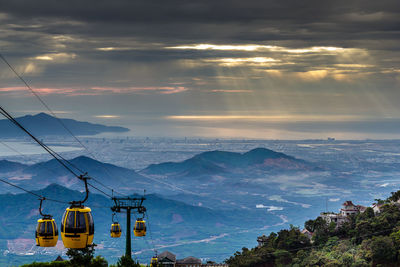 Overhead cable cars over mountains against sky during sunset