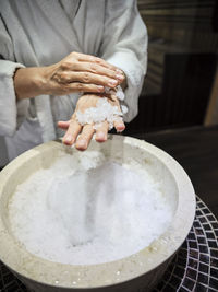 Midsection of senior woman rubbing ice on hands at spa