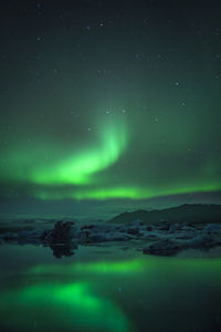 Scenic view of aurora borealis over lake against sky at night