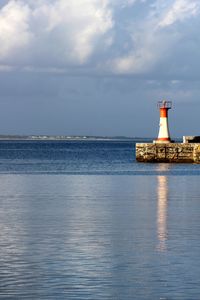 Lighthouse by sea against sky