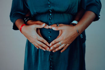 Midsection of pregnant woman with man standing against blue background