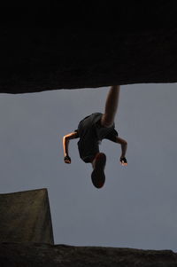 Low angle view of man jumping against clear sky