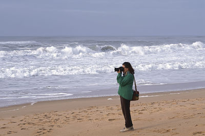 Rear view of woman standing at beach