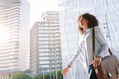 Low angle view of woman looking at modern buildings in city