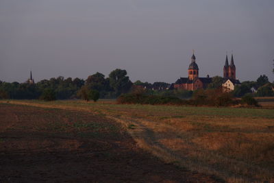 Church on field by building against sky