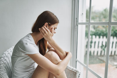 Side view of young woman sitting at home