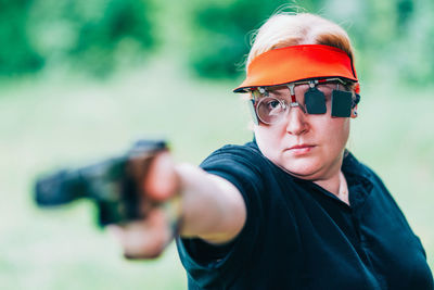 Close-up of woman aiming gun outdoors