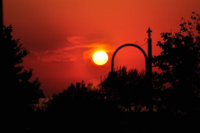 Silhouette trees against orange sky