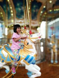 Portrait of smiling girl enjoying carousel at amusement park