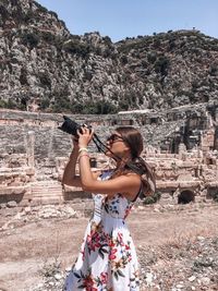 Young woman photographing against mountains