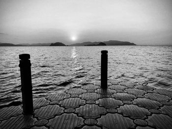 Wooden posts in sea against sky