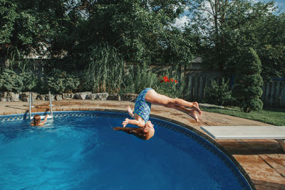Brave athletic girl in swimsuit diving in pool from springboard. child having fun in swimming pool 