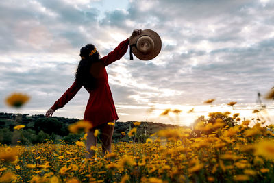 Full length of woman standing on field against sky during sunset