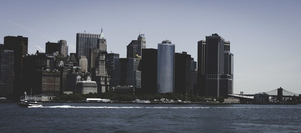 Skyscrapers by sea against clear sky