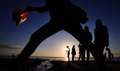 Silhouette people at beach during sunset