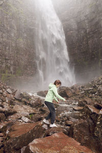 Girl on rocks at waterfall