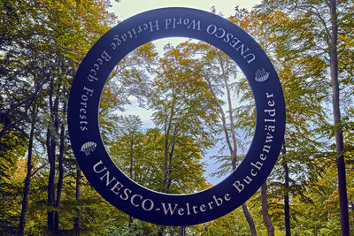 Low angle view of information sign against trees