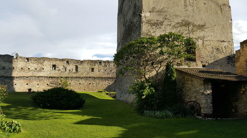 Colnic citadel on grassy field against cloudy sky