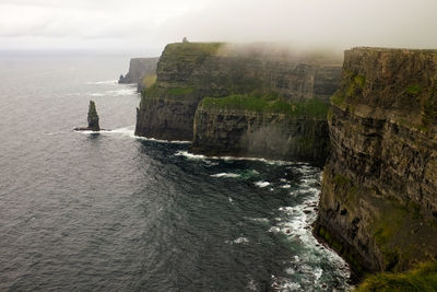 Scenic view of sea by cliff against sky