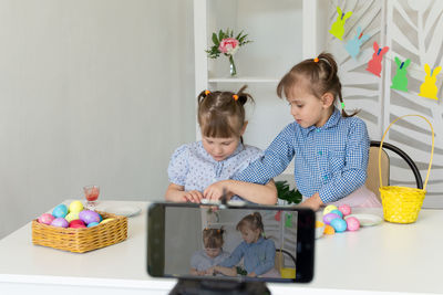 Children conduct an online master class on decorating easter eggs.